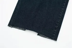 Dettaglio dell'orlo sfrangiato e dello spacco su un abito in denim blu scuro alla moda