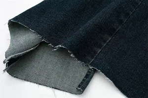 Dettaglio ravvicinato dell'orlo a taglio vivo e dello spacco su un abito in denim blu