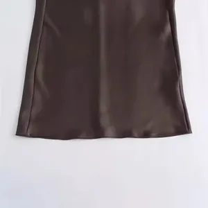 Primer plano del dobladillo liso de un vestido lencero de satén marrón oscuro para mujer.