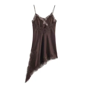 Detail of brown satin slip dress with delicate lace trim and asymmetrical hemline.