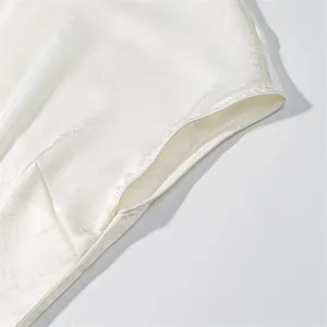 Macro view of luxurious white jacquard fabric texture and refined stitching on a slim dress
