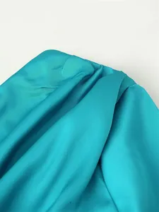 Macro detail of teal satin fabric showing elegant ruffle texture and luxury silk sheen