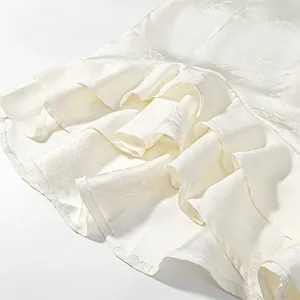 Macro detail showing the texture of white jacquard fabric with a layered ruffle hem.