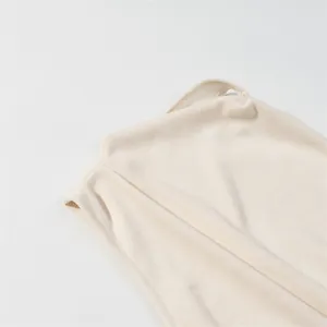 Detailed view of the beige knitted fabric and asymmetric shoulder of this chic sleeveless dress