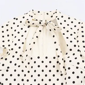 Close-up view of a chic polka dot dress collar with a stylish bow tie and cutout back.