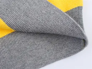 Macro detail shot showing the ribbed hem of a grey and yellow colorblock knitted sweater
