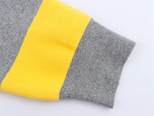 Close-up detail of gray and yellow striped knit sweater sleeve with ribbed cuff