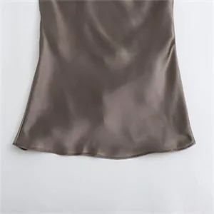 Detailansicht des glatten und glänzenden Saums eines kaffeebraunen Satin-Neckholder-Tops