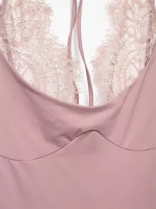 Close-up view of elegant lace patchwork and halter neckline on a pink bodysuit.