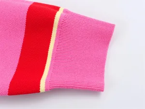Close-up of color-block knit sweater cuff with ribbed texture and vibrant pink and red hues.