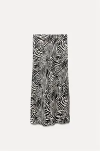 Detail view showing the elegant zebra print pattern and silky satin texture of the midi skirt.