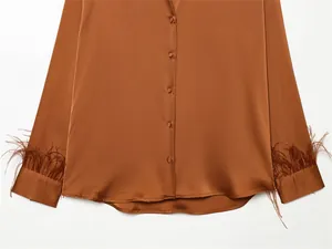 Close-up of brown satin shirt showing luxury fabric texture and feather-trimmed cuffs