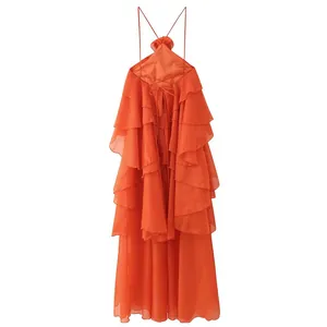 Détail d'une robe maxi orange à volants avec un col licou orné d'une fleur 3D