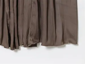 Detail des fein versäuberten Saums und der plissierten Stofftextur des braunen Kleides