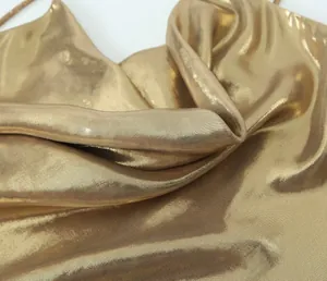 Macro view of gold metallic fabric texture and elegant drape on a backless dress