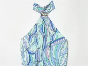 Close-up of halter neckline with silver metallic buckle on blue abstract swirl print dress