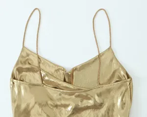 Macro detail of the golden metallic fabric and thin straps on a elegant party dress