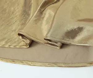 Close-up view of premium golden metallic fabric and precise stitching on camisole dress