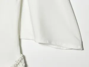 Primer plano detallado de un vestido blanco de verano con elegante bordado de lentejuelas.