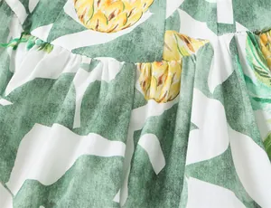 Close-up detail of tropical leaf and pineapple print on summer bustier dress fabric