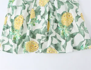 Macro view of a white dress fabric featuring a vibrant pineapple and green leaf print.
