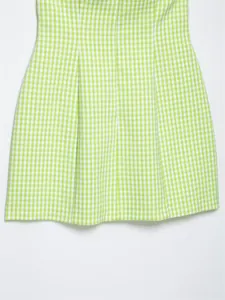 Dettaglio ravvicinato del tessuto vichy verde e bianco di un abito estivo scollo halter