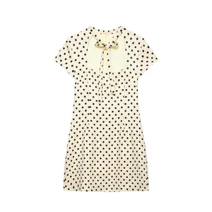 Detail view of cream polka dot mini dress featuring a bow tie and cutout neck.