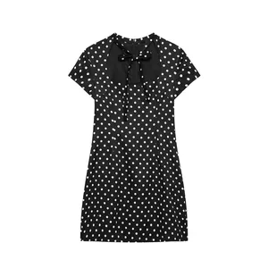 Close-up detail of black polka dot mini dress featuring a bow tie and cutout neckline.