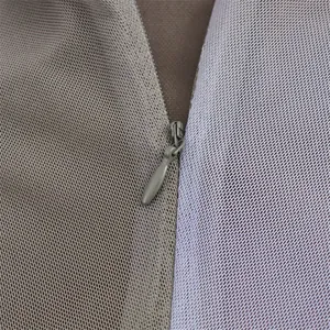 Macro detail view showing a smooth hidden zipper on textured mesh fabric garment