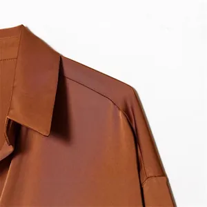 Detailed view of a brown silk-satin shirt with elegant collar and shoulder seam detail.