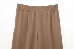 Close-up detail of the elastic waistband on stylish brown draped casual trousers.