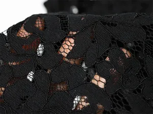 Detailansicht von feinem schwarzem floralem Spitzenstoff mit filigranen Aussparungen.