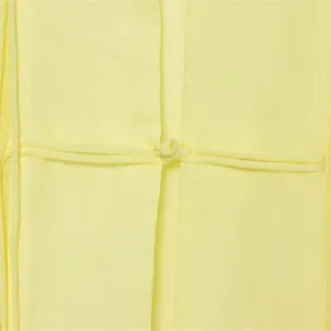 Detail van een gele gedrapeerde blouse met een knoopsluiting.