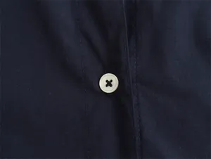 Detailed macro shot of white button on navy blue satin-textured women's shirt fabric