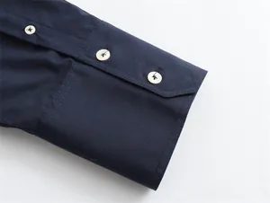 Detailed macro view of navy blue silk satin shirt cuff featuring elegant white buttons