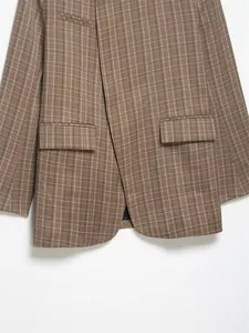 Detailed close-up of a brown plaid blazer jacket featuring elegant flap pockets and hem