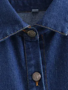 Detail shot of heart-shaped metal buttons and contrast stitching on dark blue denim vest