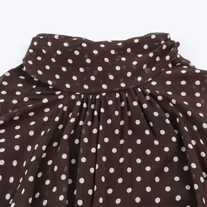 Close-up of a brown polka dot blouse collar featuring pleated details and soft fabric texture