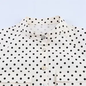 Nahaufnahme eines Polka-Dot-Hemdes für Damen mit Stehkragen und Perlmuttknöpfen.