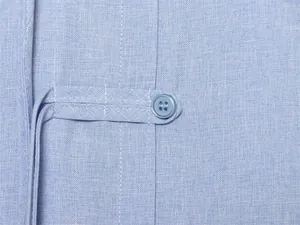 Nahaufnahme des traditionellen Knopfverschlusses an einem hellblauen Leinenhemd