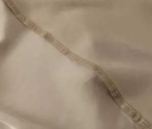 Macro view showing the high-quality overlock stitching on a metallic bronze dress