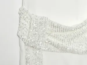 Primer plano detallado de las lentejuelas plateadas brillantes sobre tela de vestido blanca.