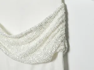Primer plano de la textura de lentejuelas plateadas en una elegante tela de vestido blanco