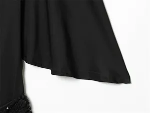 Detalle de manga acampanada negra y patchwork de lentejuelas en elegante vestido corto