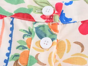 Nahaufnahme von weißen Knöpfen und lebhaften Blumenmustern auf einer Resort-Stil Bluse