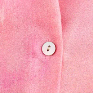 Macro detail of button and tie-dye satin fabric on a pink summer shirt