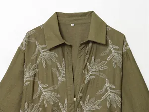Close-up of olive green long-sleeved top with elegant white floral embroidery detail