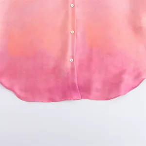 Detailed view of tie-dye print satin shirt hem with white buttons and gradient texture
