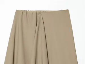 Detail view of khaki asymmetric skirt with elastic waist and soft draped pleats