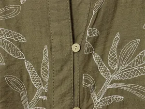 Close-up of olive green blouse with white leaf embroidery and wooden button detail